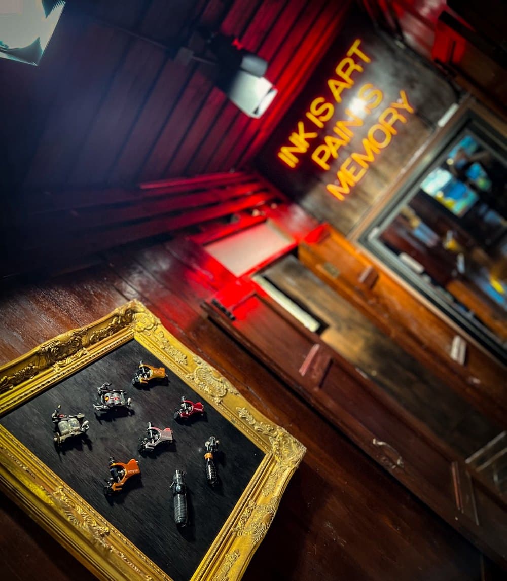 Tattoo machines framed on velvet beneath the neon