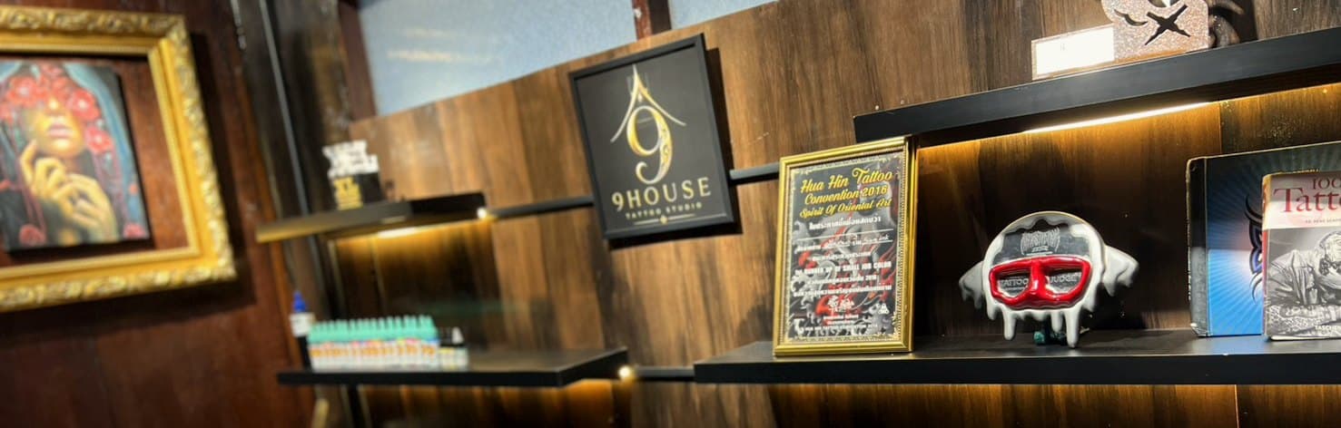 The office shelf at 9 House Tattoo — the studio emblem, the Hua Hin certificate and the desk