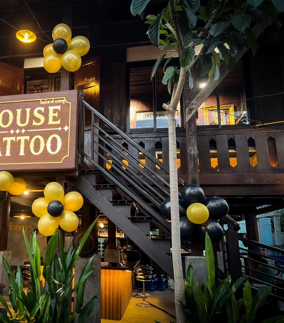 The lit 9 House Tattoo sign above the outside staircase